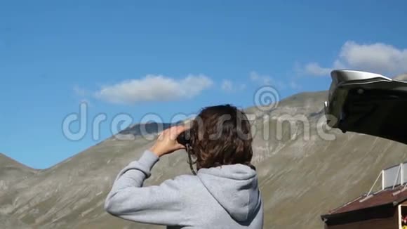 穿毛衣的年轻人带着兜帽透过望远镜视频的预览图