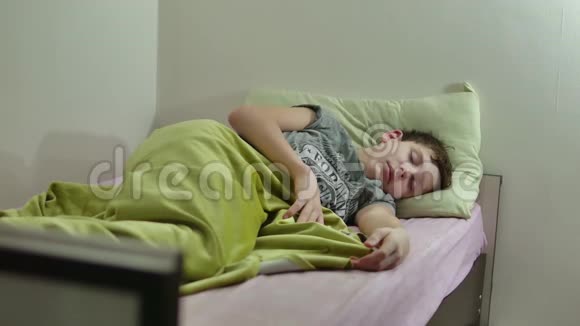 十几岁的男孩睡在床上一个在室内疲惫的小男孩视频的预览图