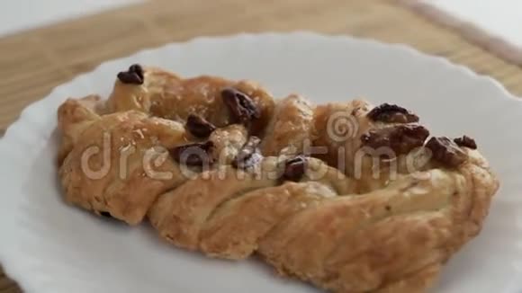 面包店烤山核桃和糖浆在白色盘子上旋转的面包的宏观视频的预览图