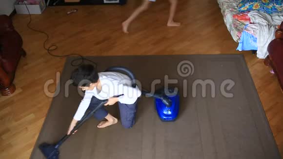 男孩用吸尘器打扫房间里的地毯视频的预览图