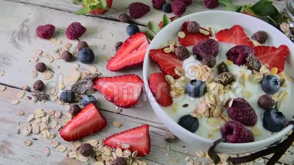 健康早餐谷类食品酸奶草莓蓝莓覆盆子和月桂在木制的乡村背景视频的预览图