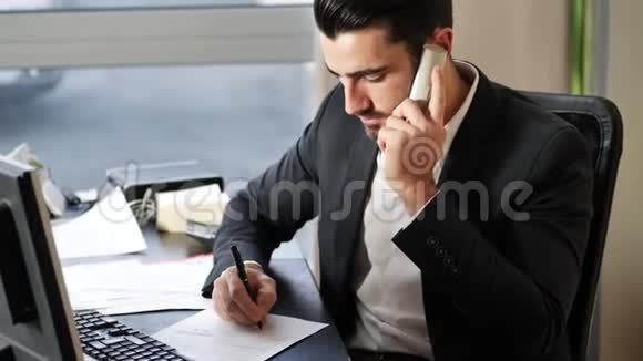快乐的年轻商人坐在办公桌前打电话视频的预览图