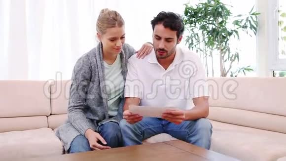 男人一边打开信封一边坐在他女朋友旁边视频的预览图