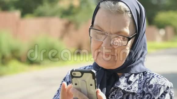 微笑的老妇人用智能手机说话视频的预览图