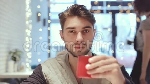 年轻人看着摄像机在咖啡馆里喝咖啡视频的预览图