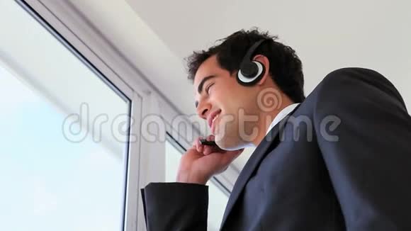 男人一边看着外面一边用耳机打电话视频的预览图