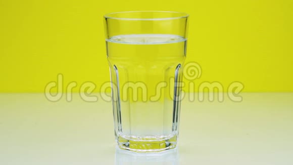 一粒止痛的泡腾药丸落入玻璃杯中在黄色背景下溶解慢镜头的阿司匹林视频的预览图