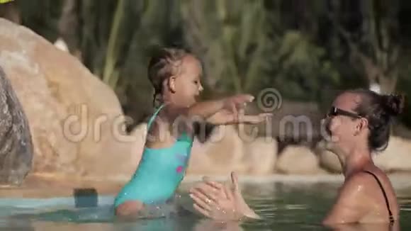 快乐漂亮的妈妈和女儿在游泳池里玩得开心视频的预览图