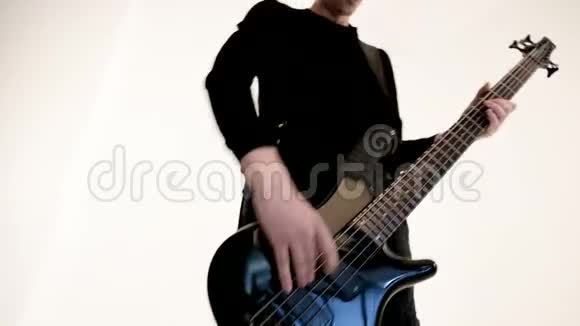 年轻的男音乐家穿着黑色衣服白色背景上有一把黑色低音吉他低音吉他演奏者演奏音乐视频的预览图