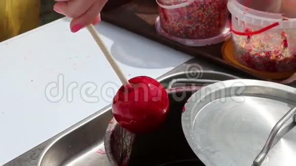 女人的手在糖浆棒上变成红苹果视频的预览图