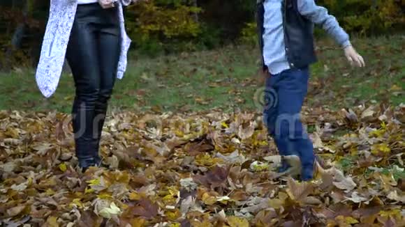 年轻漂亮的妈妈和她的小儿子在秋天的森林里玩得很开心他们跳起来把树叶扔到空中他们视频的预览图