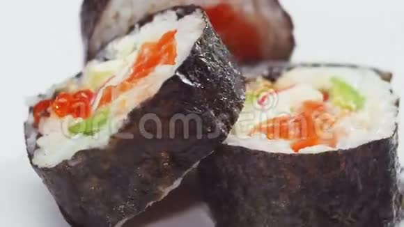 寿司卷里面有鲑鱼鳄梨和鱼子酱在白色的地上旋转视频的预览图