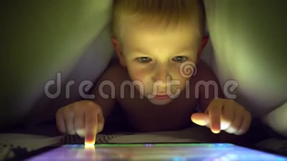 年轻的金发男孩在平板电脑上玩电脑游戏视频的预览图
