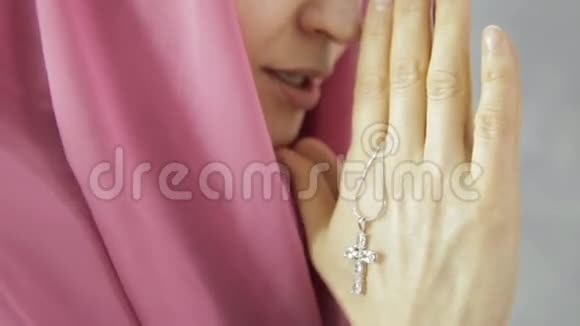 戴头巾的年轻女子在祈祷特写女性手拿着十字架的链子视频的预览图