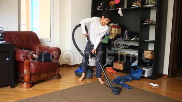 男孩用吸尘器打扫房间里的地毯视频的预览图