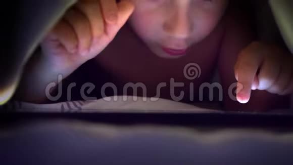 年轻的金发男孩在平板电脑上玩电脑游戏视频的预览图