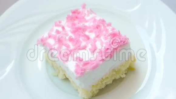 带粉红色薯片装饰的奶油蛋糕在白色盘子上旋转视频的预览图