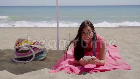 年轻女子在海滩上放松时发短信视频的预览图