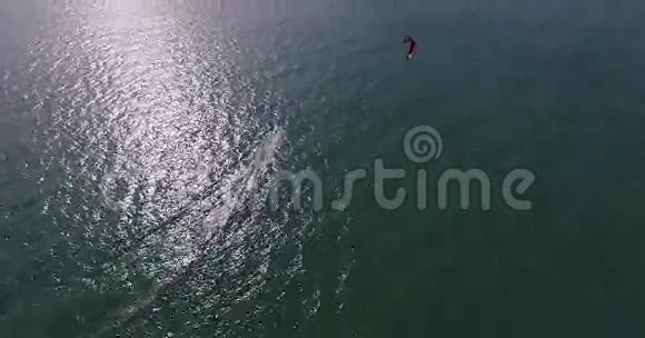 空中观看赤鸢飞人在蓝色海洋上滑行极限运动无人机镜头4K视频的预览图