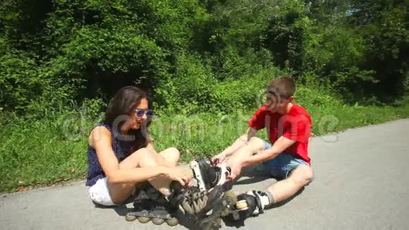 年轻的女人和男人坐在路边把他们的滚筒放在脚上视频的预览图