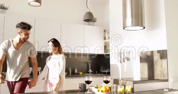 年轻的混血情侣拥抱晨曦可爱的西班牙男人亚洲女人一起在厨房视频的预览图