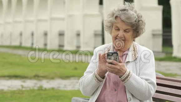 老年妇女在户外手持银色智能手机视频的预览图