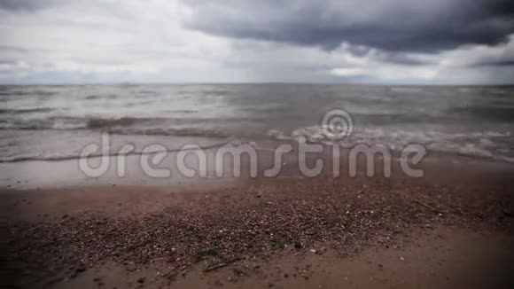 海滩上的小海浪带着小石头灰色的天空夏天滑锅视频的预览图