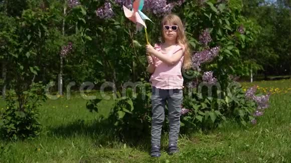 一个小女孩在一个公园里旁边是春天盛开的紫丁香视频的预览图