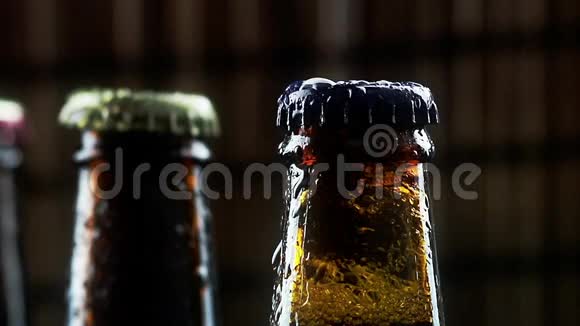 男子脱开三瓶新鲜啤酒泡沫和滴在黑暗背景酒吧视频的预览图