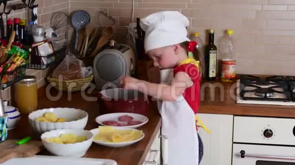 可爱的小女孩做晚餐小女孩在厨房准备食物可爱的小女孩打扮得像个厨师视频的预览图