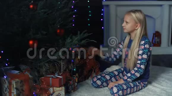 一个小女孩坐在圣诞树下正在考虑礼物视频的预览图