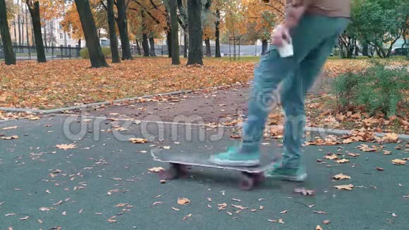 滑雪者拿起滑板手中的水滴再次捡起继续走秋天的公园视频的预览图