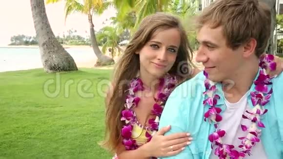微笑年轻情侣爱上雷坐在棕榈树下拥抱视频的预览图