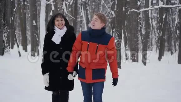 一对年轻的夫妇在冬季森林里慢动作散步视频的预览图