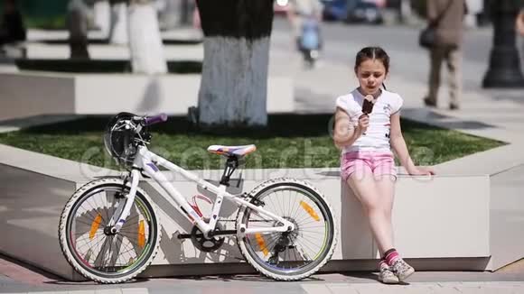 可爱的小女孩在阳光明媚的夏日在城市公园吃冰淇淋视频的预览图