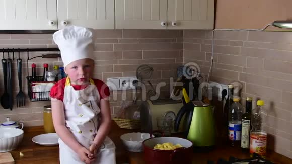 可爱的小女孩做晚餐小女孩在厨房准备食物可爱的小女孩打扮得像个厨师视频的预览图