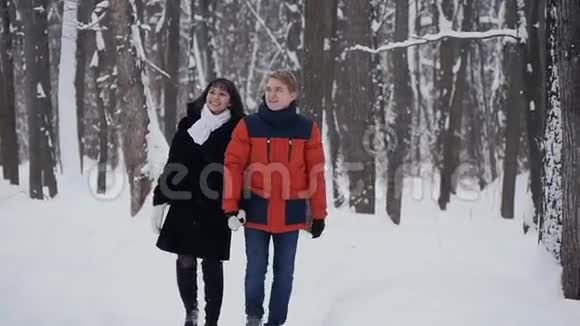 一对年轻的夫妇在冬季森林里慢动作散步视频的预览图