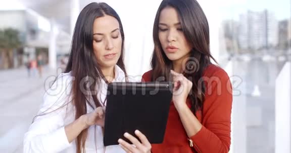 在户外看平板电脑的年轻女子视频的预览图