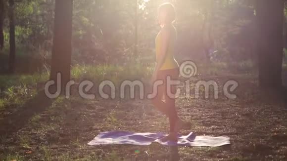 女孩在森林日落时练习瑜伽慢动作视频的预览图