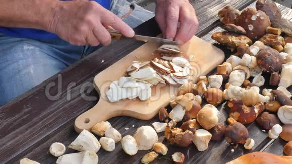 漂亮的野生蘑菇用刀切成木砧板上的小块手把牛肝菌切成薄片视频的预览图
