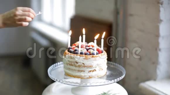 女厨师在美丽的奶油草莓蓝莓覆盆子蛋糕上点燃蜡烛视频的预览图