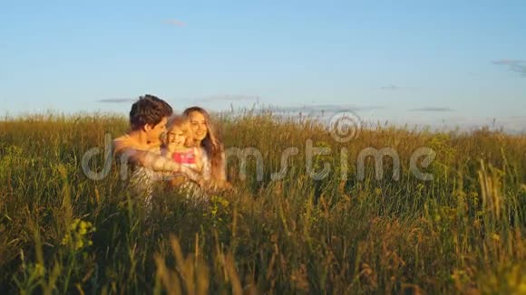 快乐的一对夫妇坐在田野里看日落视频的预览图