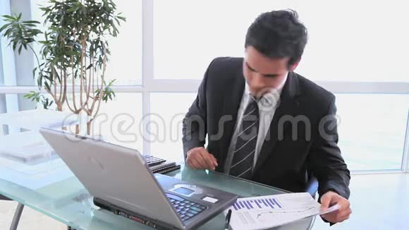 一个商人用计算器检查他的电子表格视频的预览图