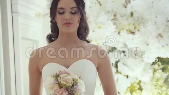 漂亮的新娘穿着婚纱在工作室里放着鲜花视频的预览图