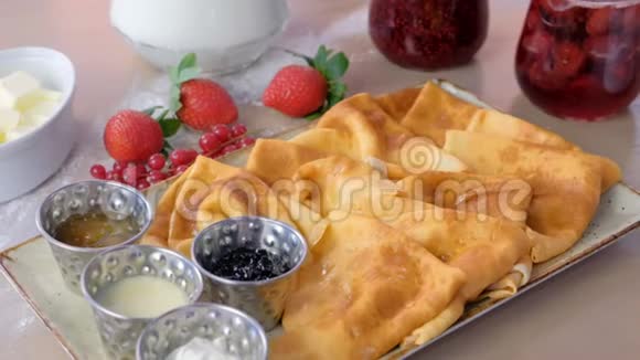 俄罗斯传统煎饼布里尼提供果酱酸奶油和草莓盘特写镜头视频的预览图