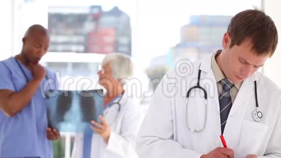 严肃的医生在他的剪贴板上当着同事的面写字视频的预览图