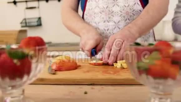 一个男人和女人用草莓准备水果沙拉的手的特写视频的预览图