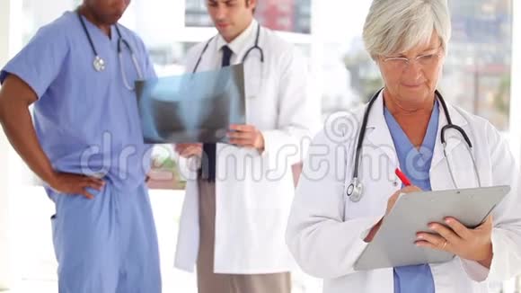 严肃的医生在她的团队前面的剪贴板上写字视频的预览图