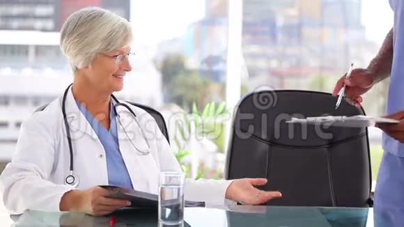 微笑着向护士出示文件的成熟医生视频的预览图