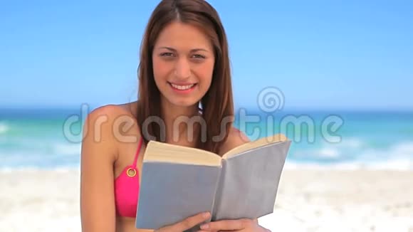 微笑的黑发女人一边捧着书一边享受阳光视频的预览图
